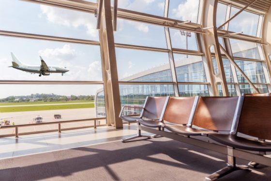 View from the airport lounge to landing aircraft, Car airfield maintenance at airport apron. Airplane travel concept